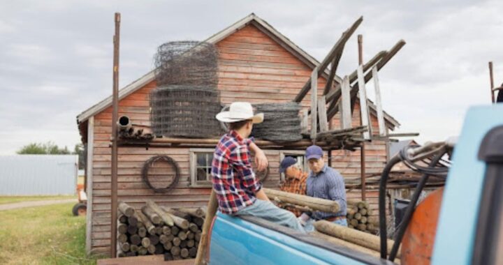 Homeowners and barn repair workers loading materials beside a wooden barn in New York, preparing for maintenance to protect stored belongings from damage.